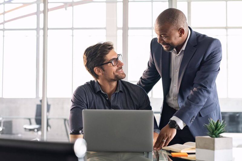 Two businessmen working on a laptop in an office.