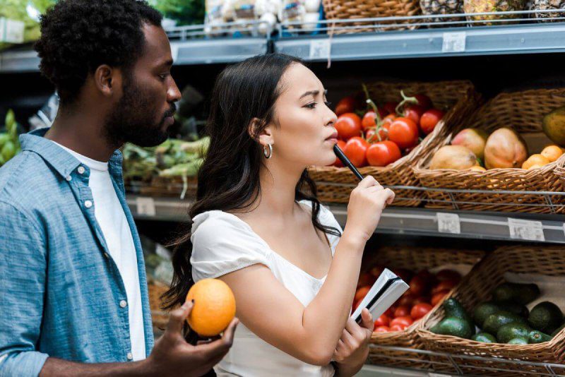 A man and woman looking at fruits and vegetables in a grocery store.
